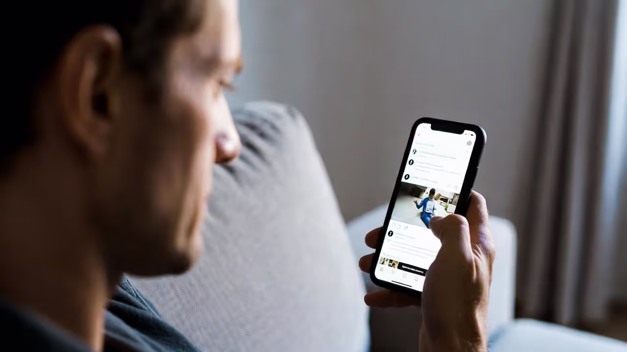 Person looking at a smartphone with a tense expression while sitting alone on a couch