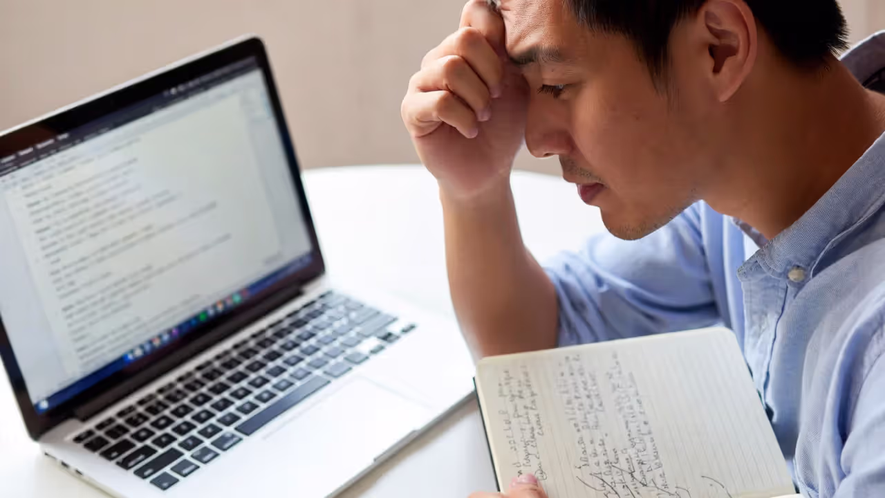 Professional reviewing heavily corrected notes with a tense expression, illustrating perfectionism and self-criticism